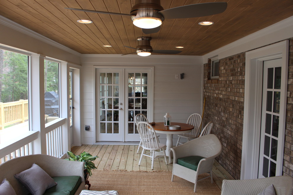 This is an example of a large classic back screened veranda in Atlanta with natural stone paving and a roof extension.