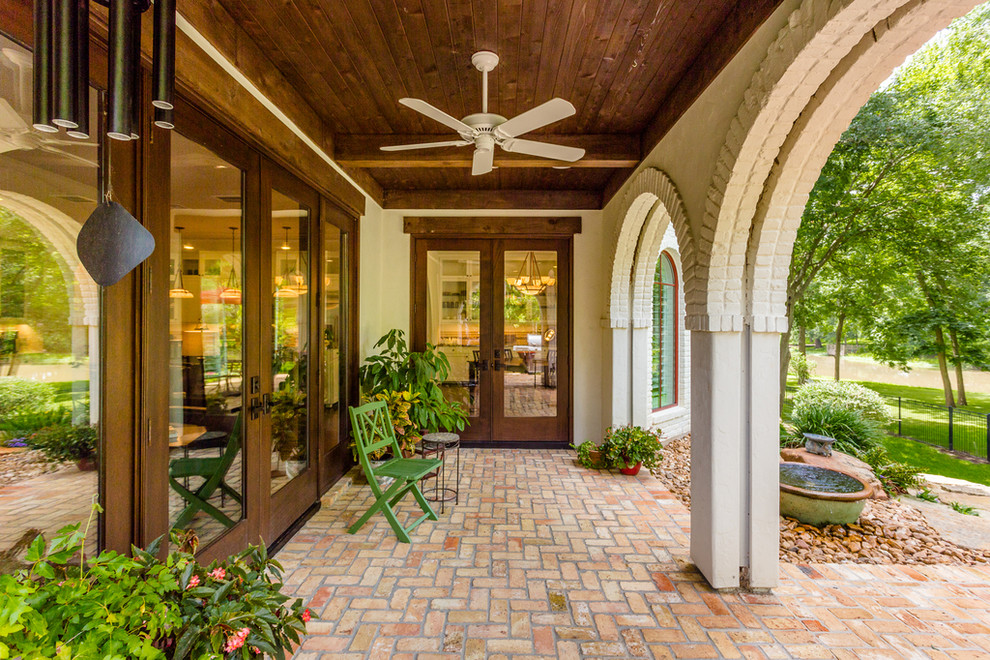 This is an example of a large mediterranean veranda in Houston with brick paving, a roof extension and a potted garden.