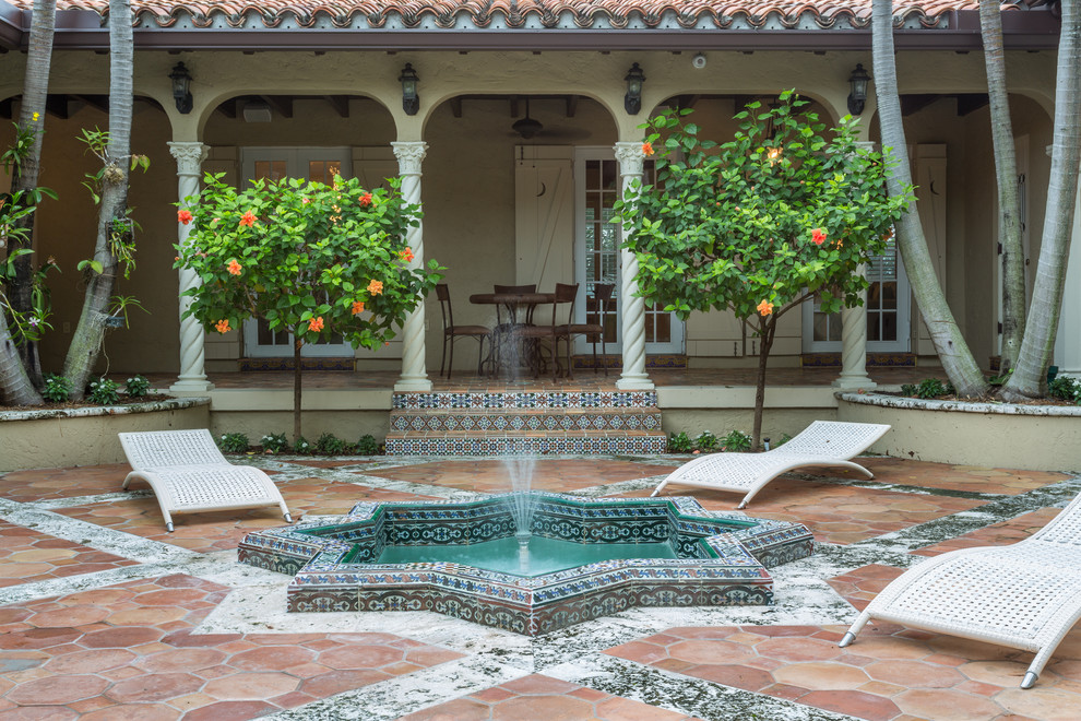 Photo of a mediterranean veranda in Miami with a water feature and tiled flooring.