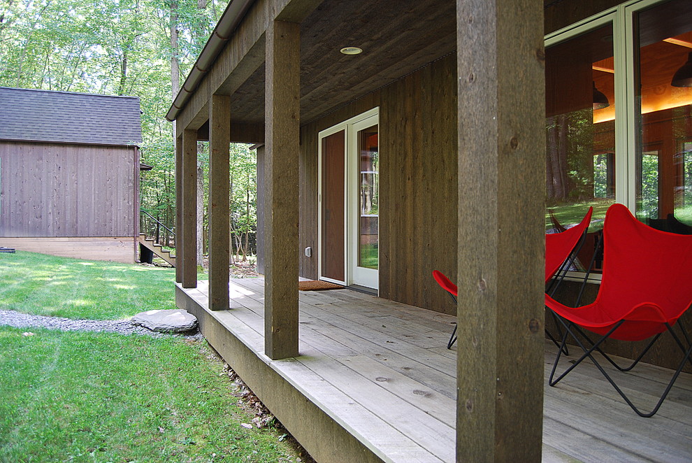 Idée de décoration pour un porche d'entrée de maison design avec une terrasse en bois et une extension de toiture.