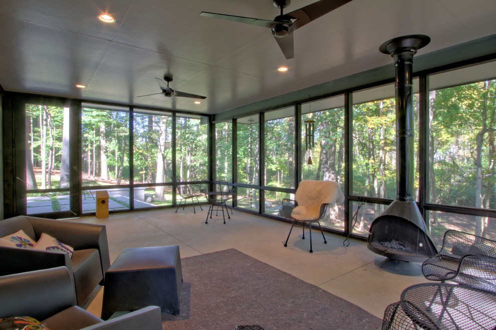 This is an example of a large 1950s screened-in back porch design in Indianapolis with a roof extension.