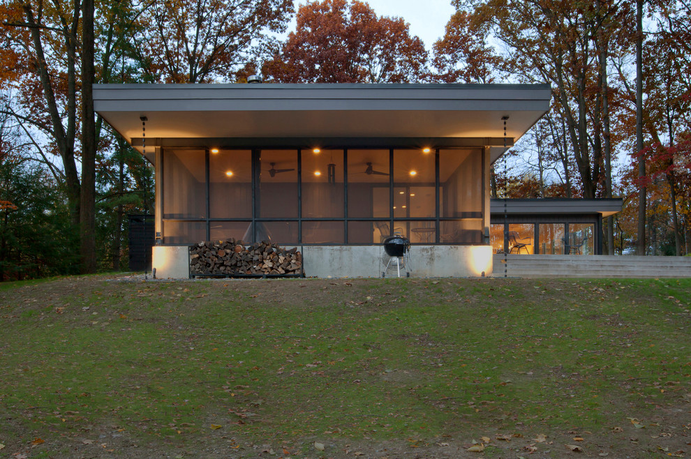 Cette image montre un porche d'entrée de maison arrière vintage de taille moyenne avec une moustiquaire, des pavés en béton et une extension de toiture.