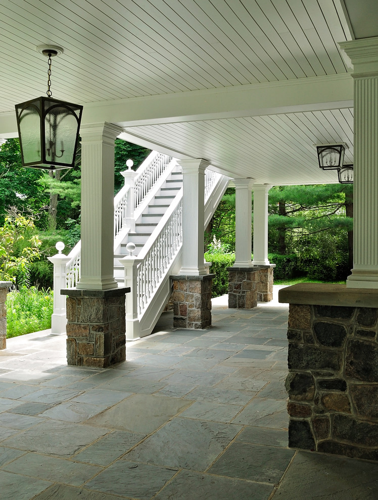 Immagine di un grande portico classico davanti casa con pavimentazioni in pietra naturale e un tetto a sbalzo