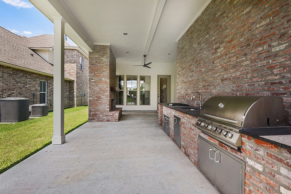 This is an example of a large classic back veranda in New Orleans with an outdoor kitchen and a roof extension.