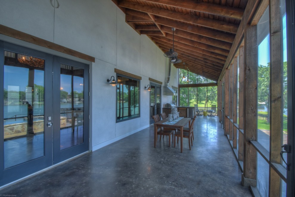 Inspiration for a large rustic concrete screened-in back porch remodel in Austin with a roof extension
