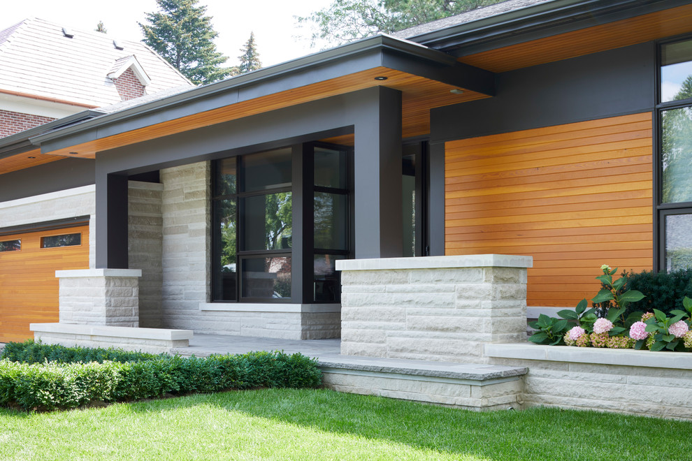 This is an example of a medium sized modern front veranda in Toronto with a potted garden, natural stone paving and a roof extension.