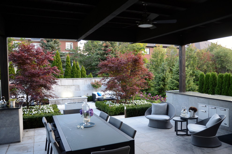 Cette photo montre une petite terrasse arrière moderne avec une cuisine d'été, des pavés en pierre naturelle et une extension de toiture.