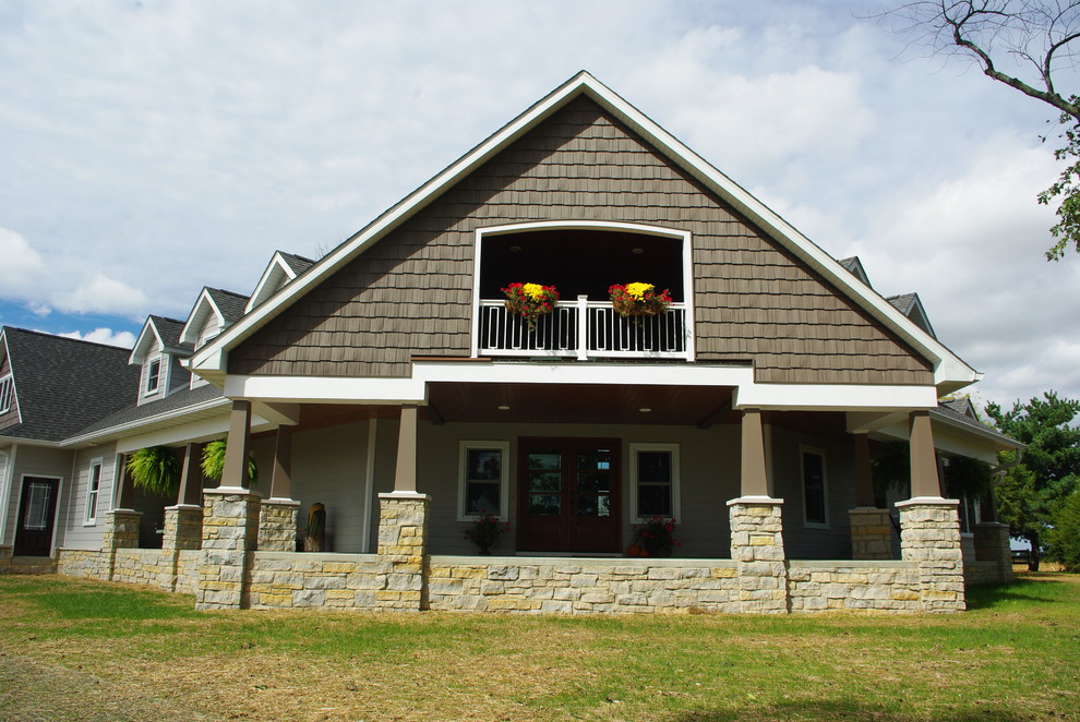 Bild på en stor lantlig veranda framför huset, med naturstensplattor och takförlängning