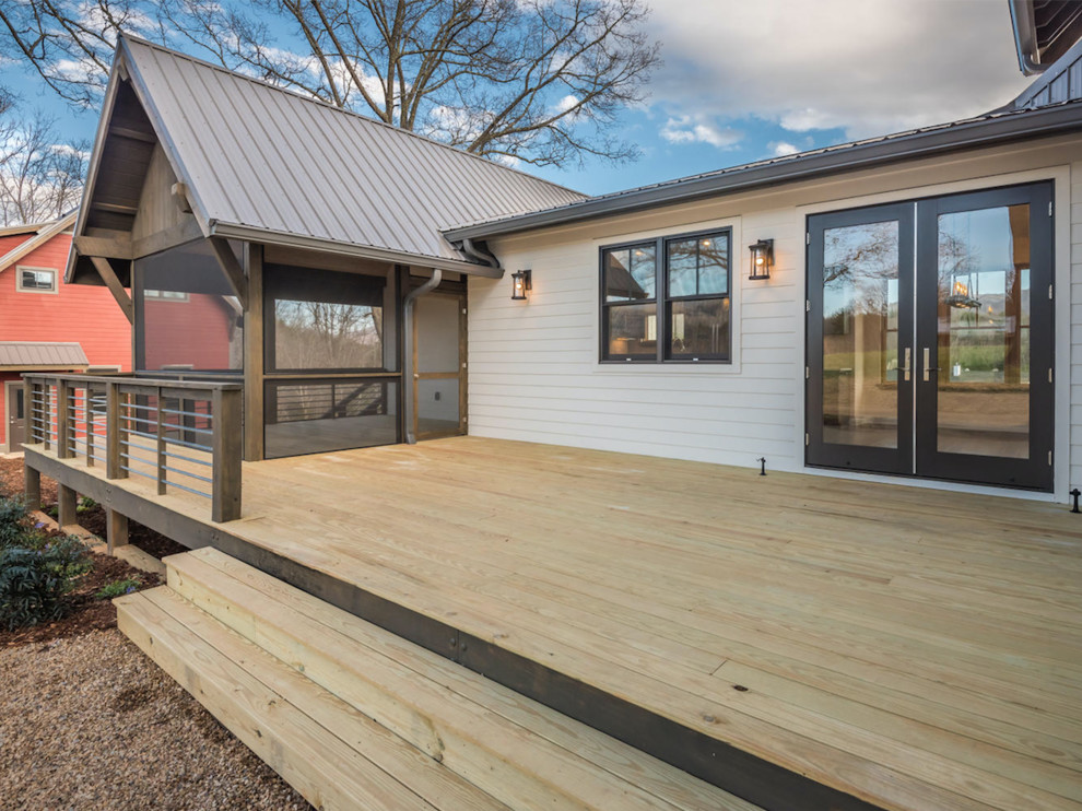 Cette photo montre un grand porche d'entrée de maison avant nature avec une moustiquaire, une terrasse en bois et une extension de toiture.