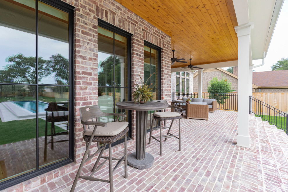 Cette image montre un grand porche d'entrée de maison arrière rustique avec des pavés en brique et une extension de toiture.