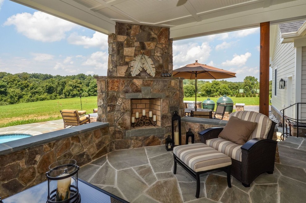 Imagen de terraza de estilo de casa de campo grande en patio trasero con adoquines de piedra natural