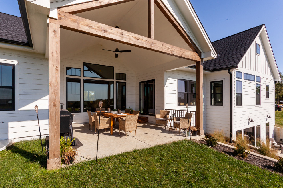 Idée de décoration pour un grand porche d'entrée de maison arrière champêtre avec une dalle de béton et une extension de toiture.