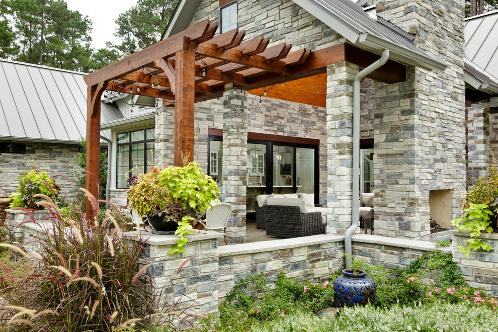 Imagen de terraza de estilo de casa de campo de tamaño medio en patio delantero con chimenea, adoquines de hormigón y pérgola