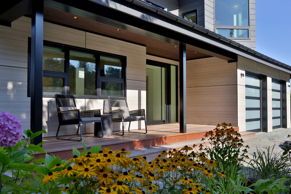Exemple d'un grand porche d'entrée de maison avant moderne avec une terrasse en bois et une extension de toiture.