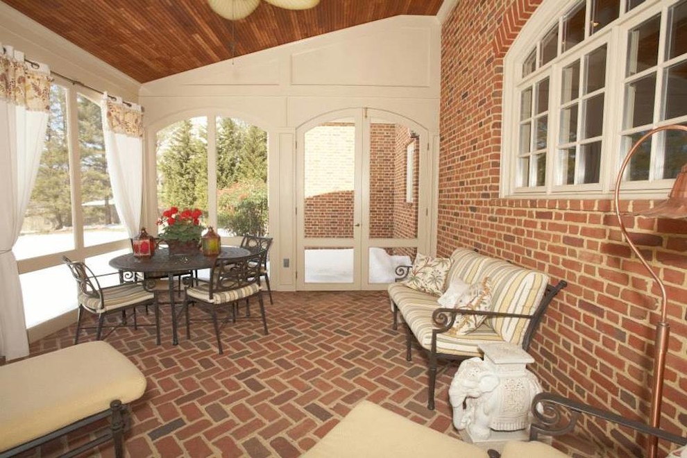 Mid-sized elegant brick screened-in back porch photo in DC Metro with a roof extension