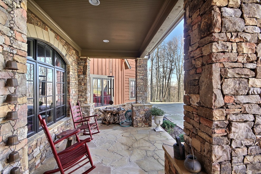 Large mountain style stone front porch photo in Atlanta with a roof extension