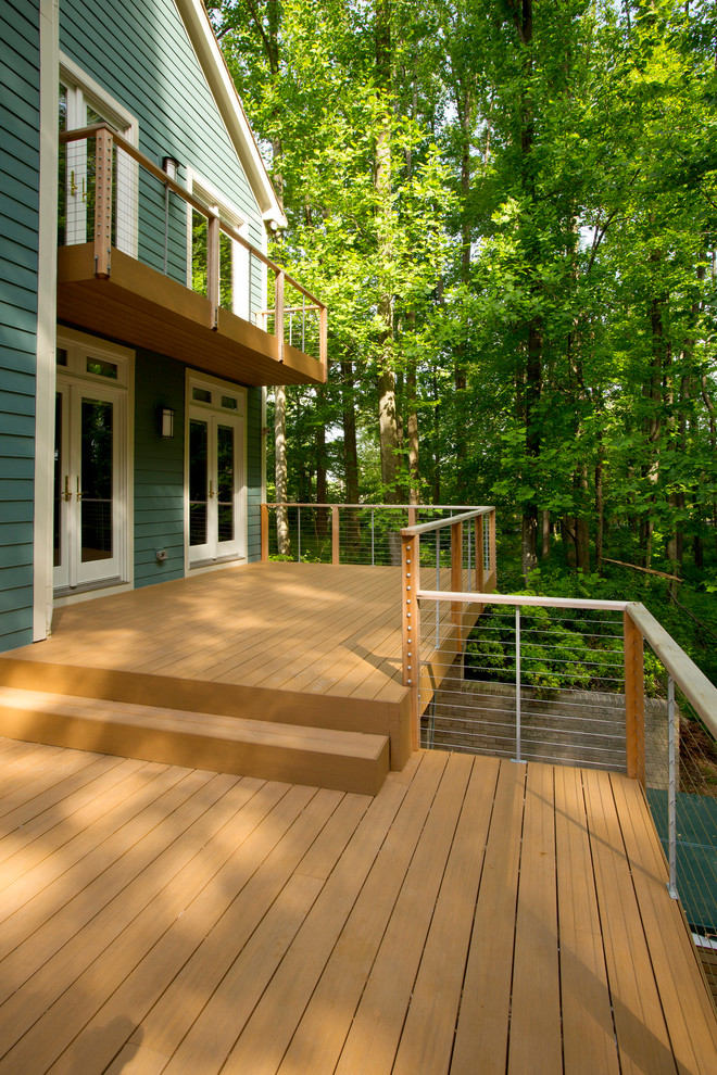 Cette image montre un grand porche d'entrée de maison arrière traditionnel avec une terrasse en bois.