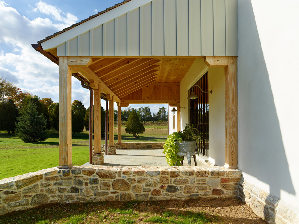 Inspiration för en lantlig veranda framför huset, med naturstensplattor och takförlängning