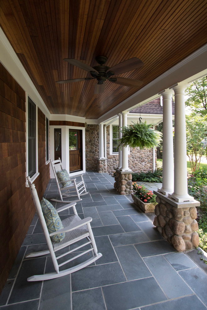 Large classic front porch idea in New York with a roof extension