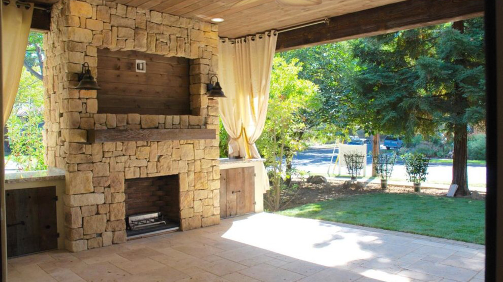 This is an example of a large transitional stone side porch design in San Francisco with a fireplace and a roof extension.