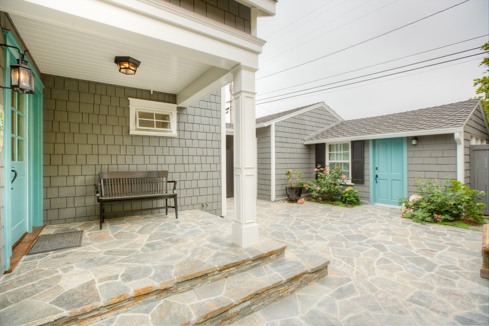Cette photo montre un porche d'entrée de maison bord de mer avec des pavés en pierre naturelle et une extension de toiture.