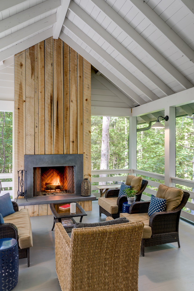 Inspiration pour un grand porche d'entrée de maison arrière rustique avec une cheminée et une extension de toiture.
