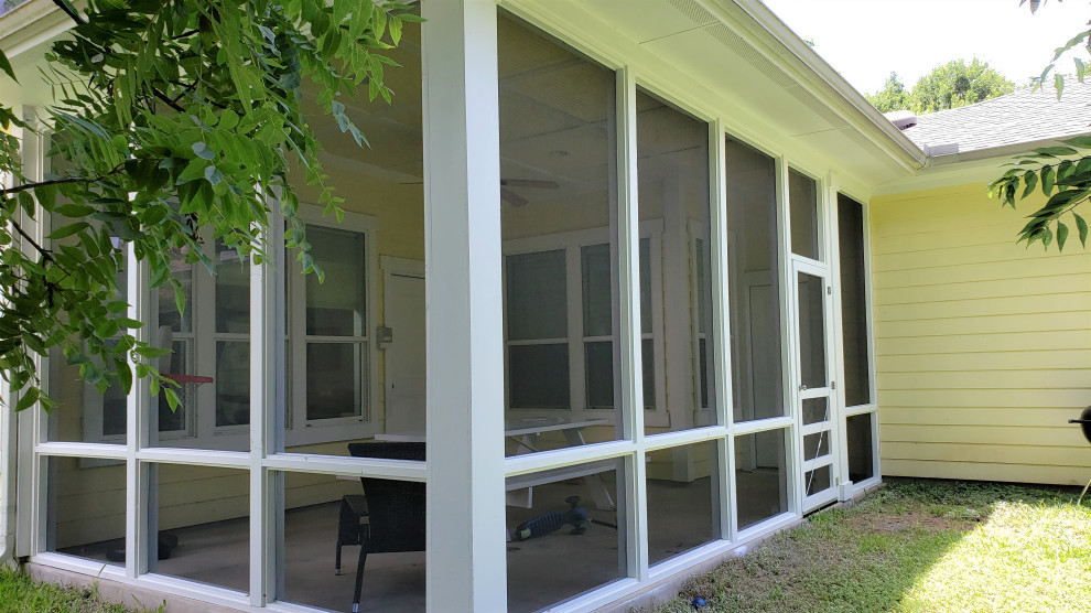 Cette image montre un porche d'entrée de maison arrière craftsman de taille moyenne avec une moustiquaire, une dalle de béton et une extension de toiture.