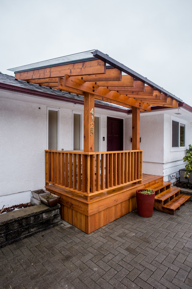 Exempel på en mellanstor modern veranda framför huset, med trädäck och en pergola