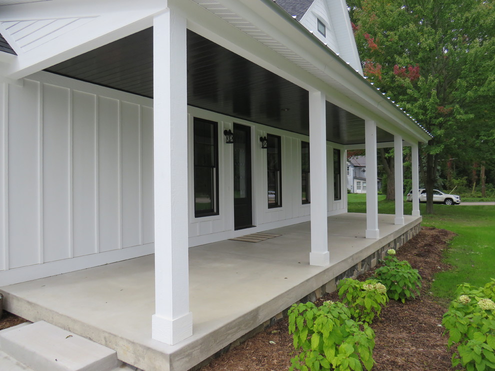 Aménagement d'un grand porche d'entrée de maison avant campagne avec une dalle de béton et une extension de toiture.