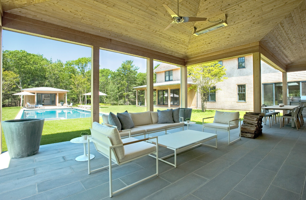 This is an example of a large traditional back veranda in New York with a fire feature and natural stone paving.