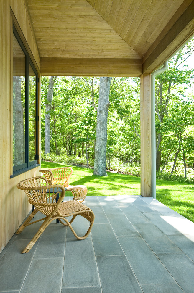 Large transitional stone back porch photo in New York