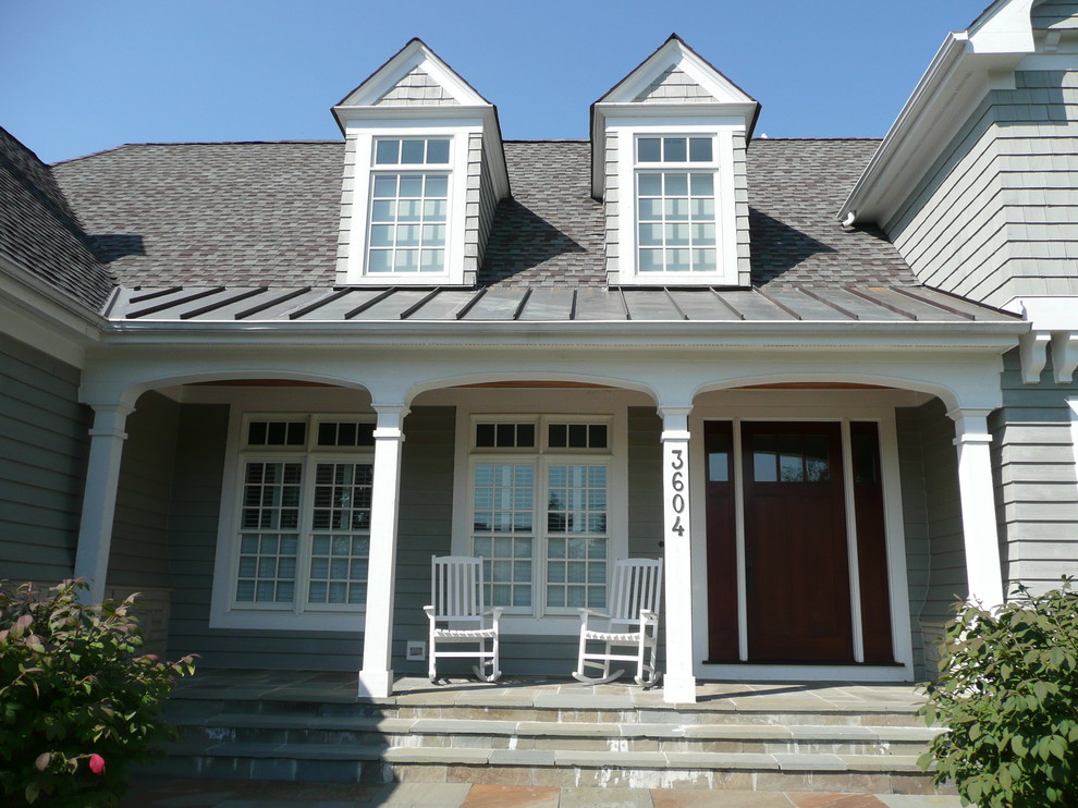 Cette image montre un grand porche d'entrée de maison avant traditionnel avec des pavés en pierre naturelle et une extension de toiture.