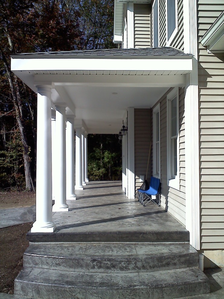 Cette photo montre un porche d'entrée de maison avant chic avec du béton estampé et une extension de toiture.