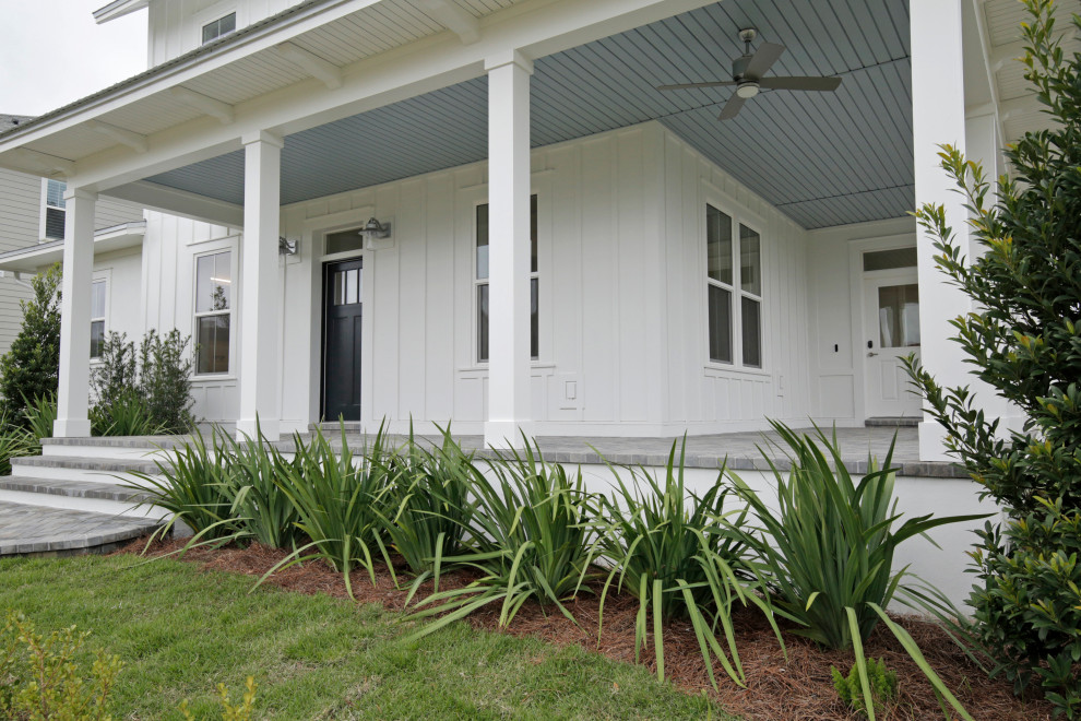 Ejemplo de terraza de estilo de casa de campo de tamaño medio en patio delantero y anexo de casas con adoquines de ladrillo