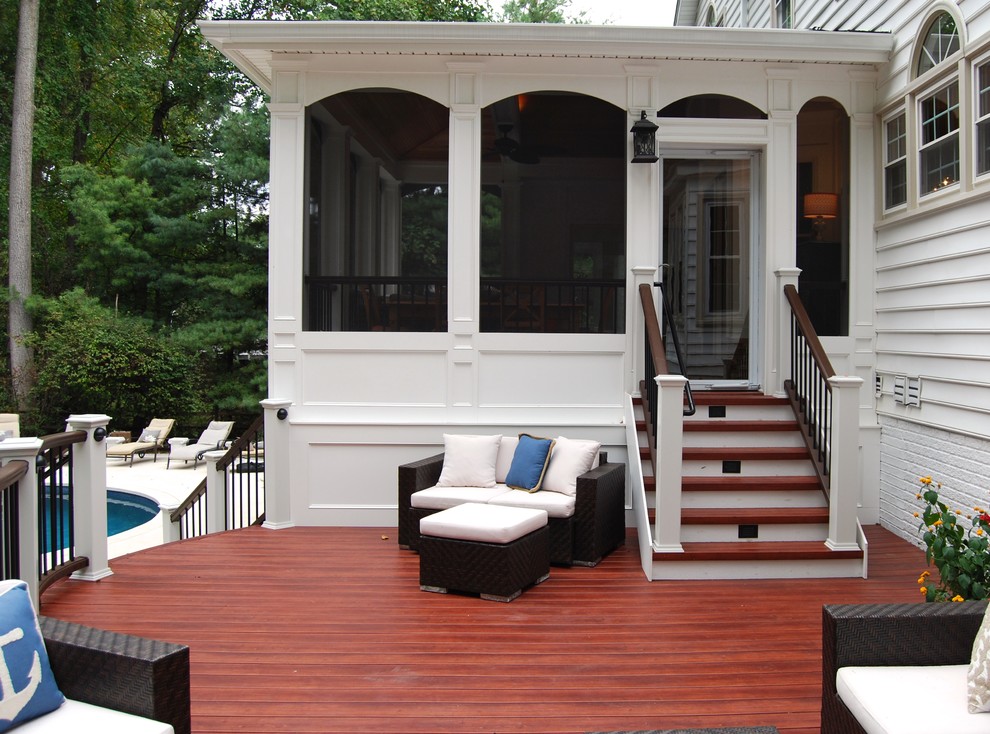 This is an example of a large traditional screened-in back porch design in DC Metro with decking and a roof extension.