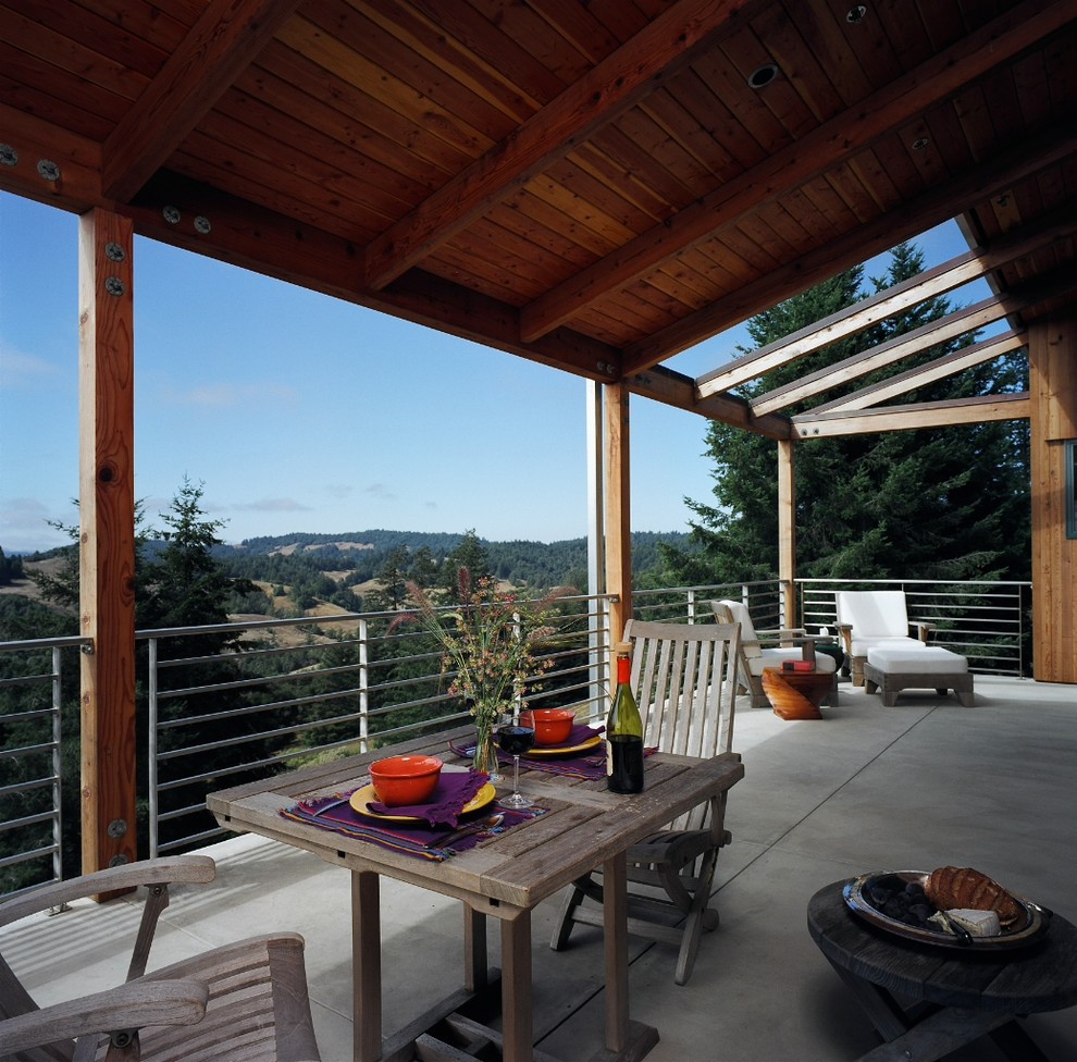This is an example of a contemporary back veranda in San Francisco with concrete slabs and a roof extension.