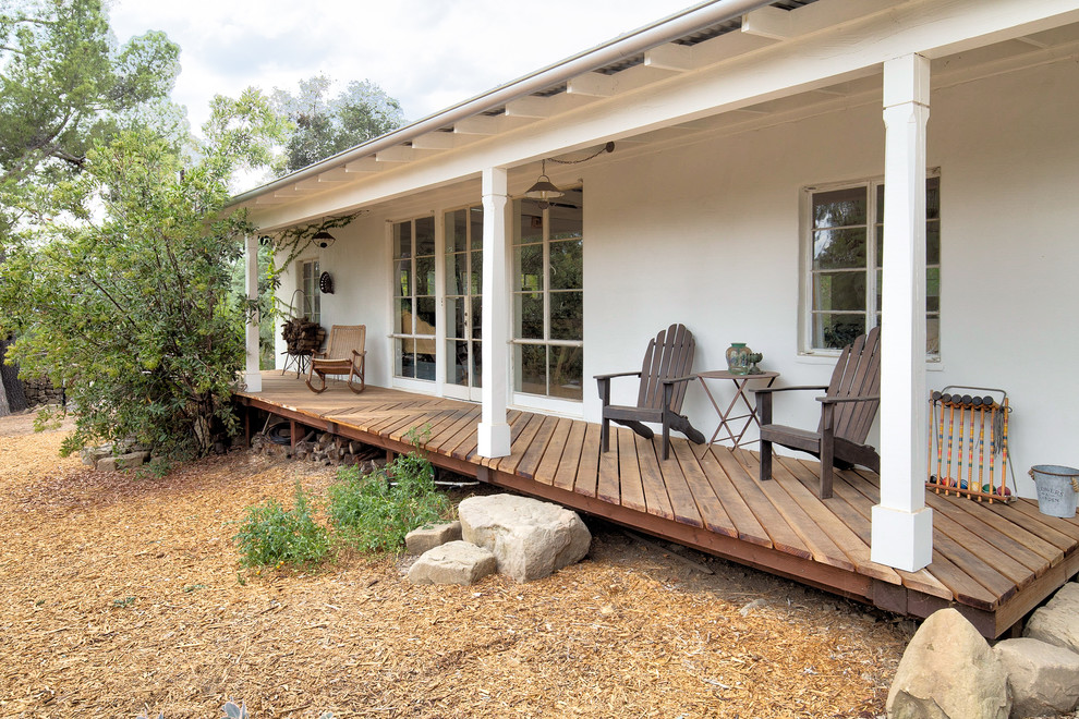 Réalisation d'un grand porche d'entrée de maison arrière tradition avec une terrasse en bois et une extension de toiture.