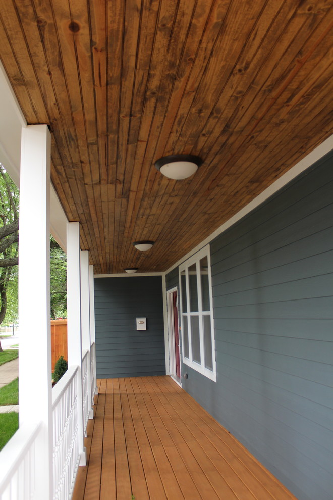 This is an example of a large front porch design in Chicago with a roof extension.