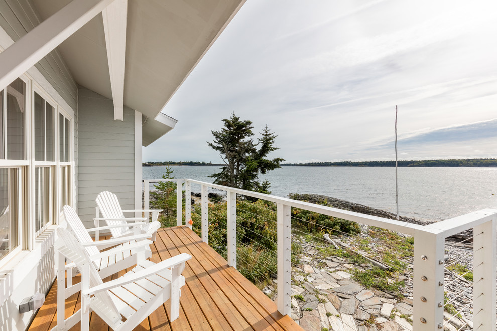 Cette photo montre un porche d'entrée de maison arrière bord de mer de taille moyenne avec une extension de toiture et une terrasse en bois.