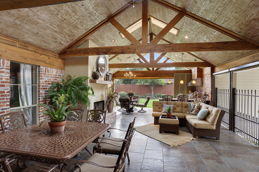 This is an example of a large rustic back veranda in New Orleans with an outdoor kitchen, tiled flooring and a roof extension.