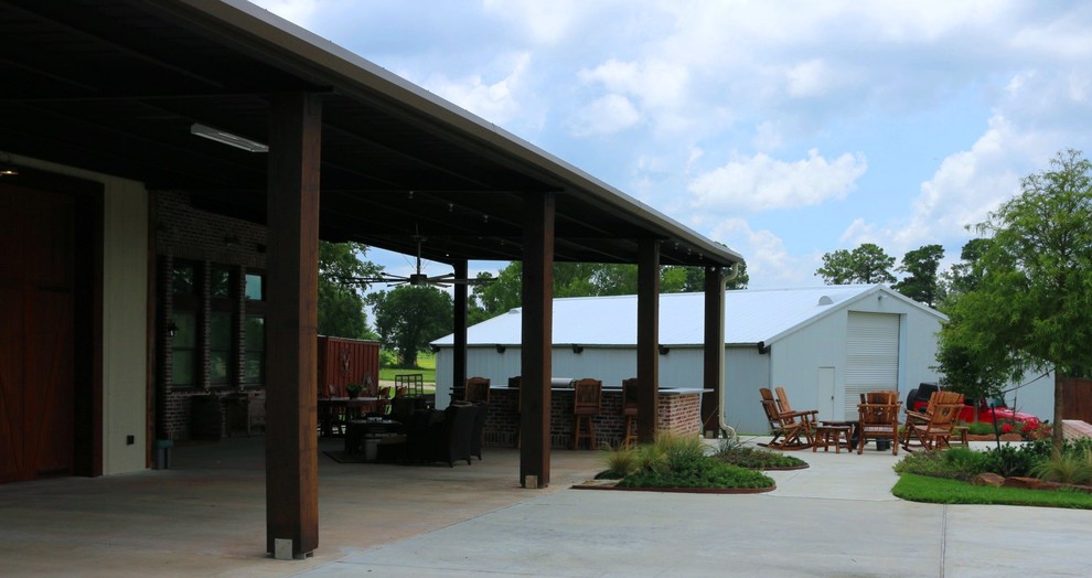 Aménagement d'un grand porche d'entrée de maison avant campagne avec une cuisine d'été, une dalle de béton et une extension de toiture.