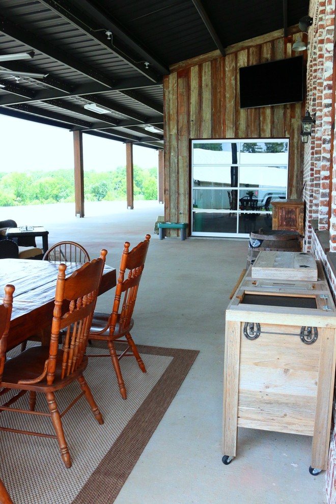 This is an example of a large farmhouse front veranda in Houston with an outdoor kitchen, concrete slabs and a roof extension.