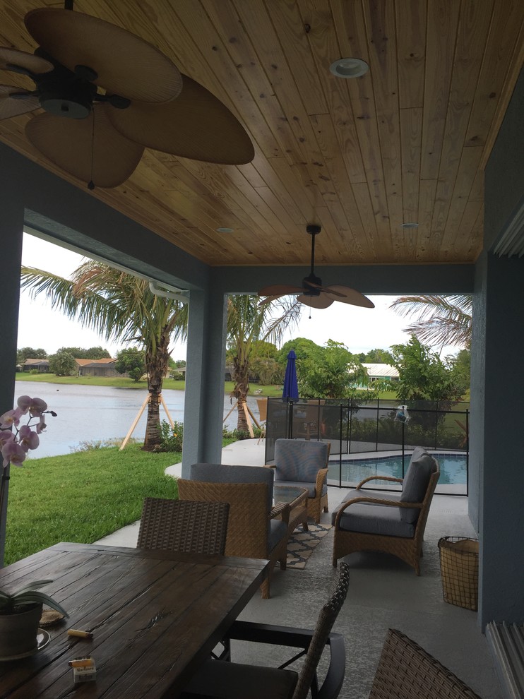 Inspiration for a mid-sized coastal concrete back porch remodel in Miami with a roof extension