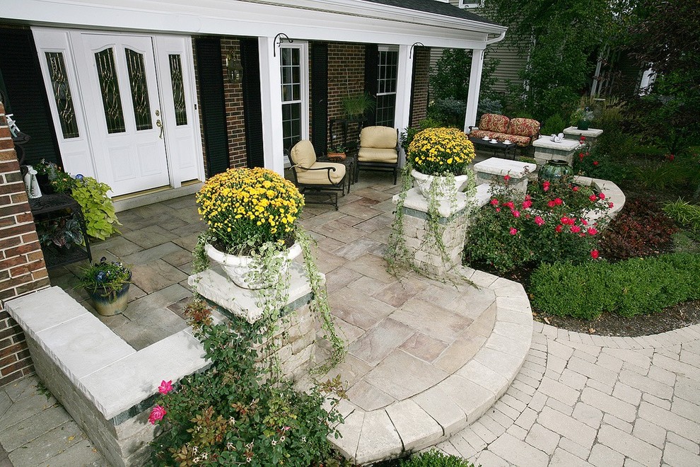 This is an example of a medium sized traditional front veranda in Chicago with a roof extension, a water feature and brick paving.