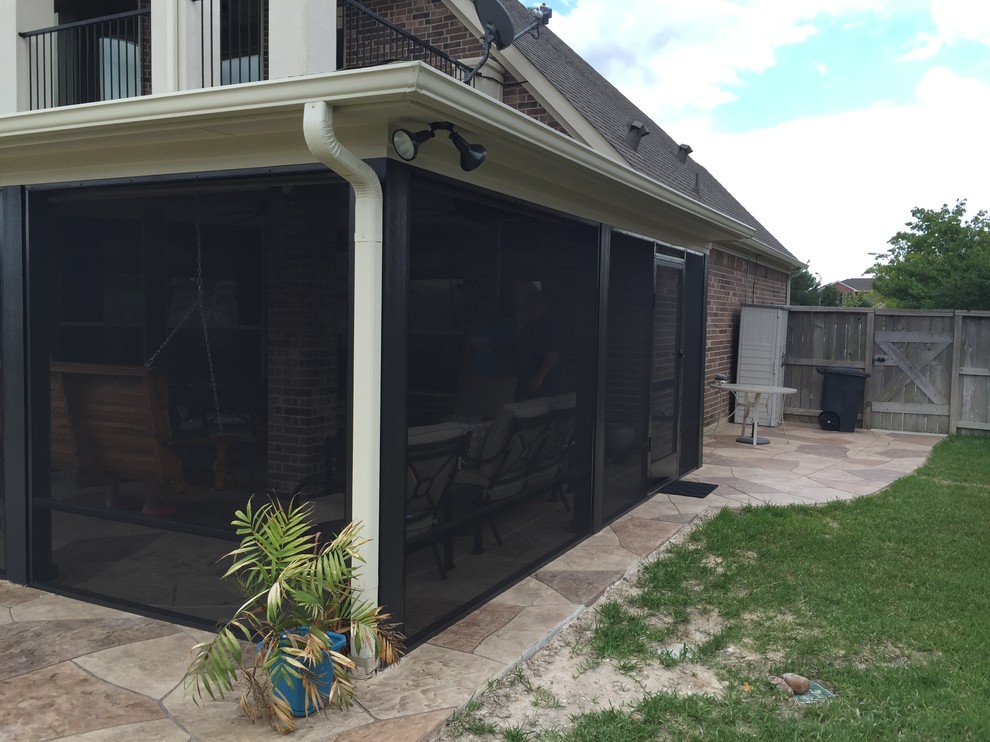 Photo of a medium sized classic back screened veranda in Houston with stamped concrete and a roof extension.