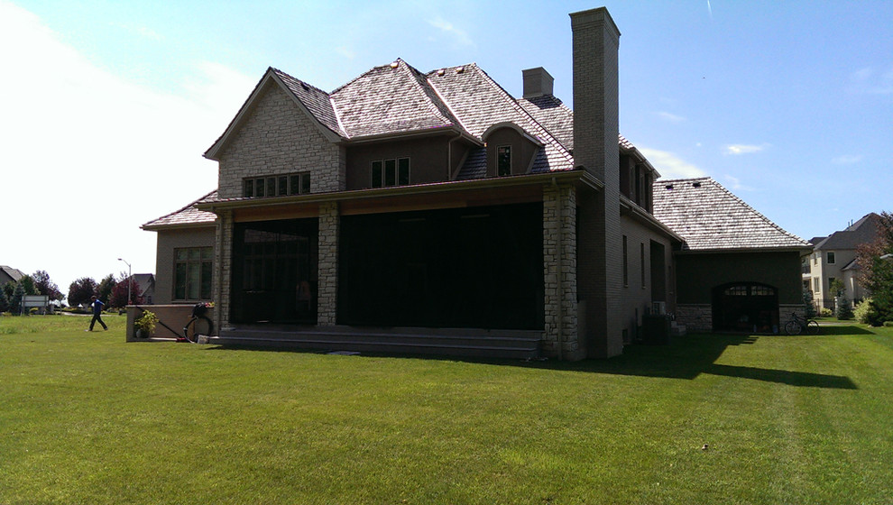Cette image montre un grand porche d'entrée de maison arrière chalet avec une cuisine d'été, une terrasse en bois et une extension de toiture.