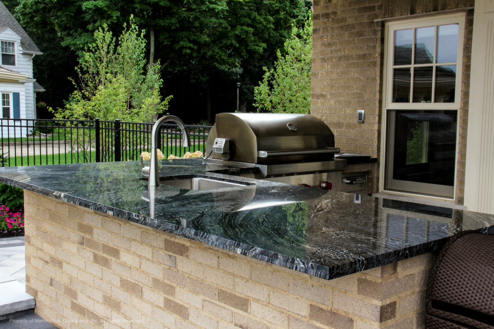 Photo of a large traditional back veranda with an outdoor kitchen, concrete paving and a roof extension.