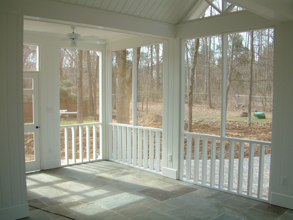Exemple d'un grand porche d'entrée de maison arrière chic avec une moustiquaire, des pavés en pierre naturelle et une pergola.
