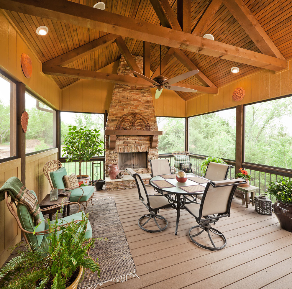 Idée de décoration pour un porche d'entrée de maison tradition avec un foyer extérieur, une terrasse en bois et une extension de toiture.