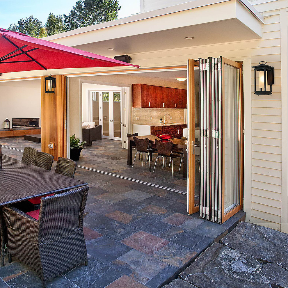 Modelo de terraza clásica renovada de tamaño medio en patio delantero con adoquines de hormigón y pérgola